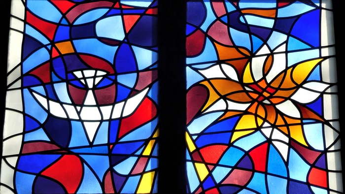 Lebendige Glasmalereien mit abstrakten floralen und geometrischen Mustern in satten Blautönen, Rottönen und Gelb.