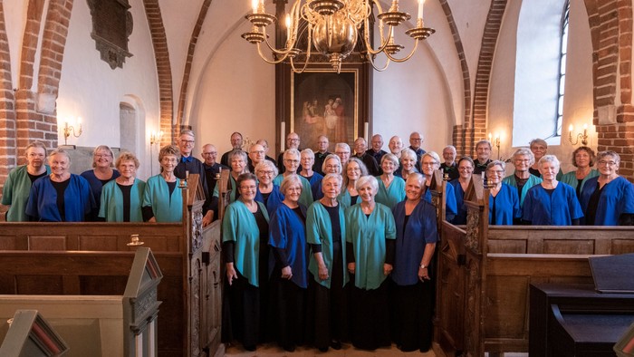 Gruppe af mennesker i blå og grønne skjorter, der poser i en kirke.