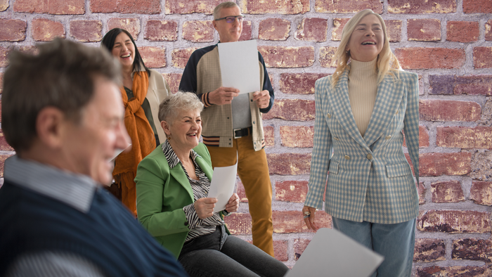 Ein Team trifft sich in einem Raum mit Backsteinwand und diskutiert.