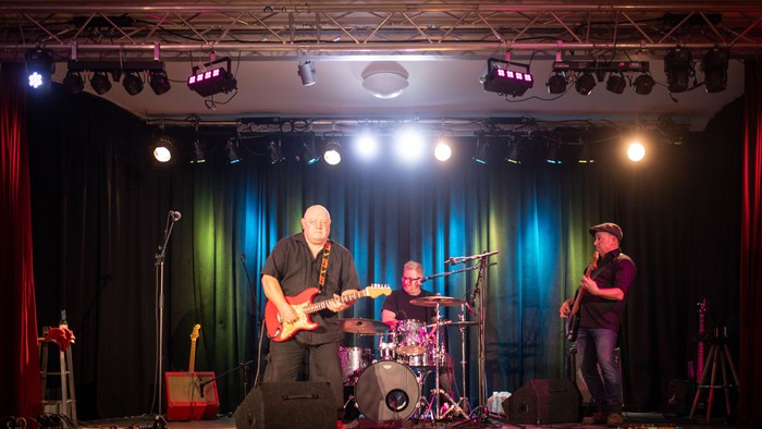 Eine Band spielt auf einer Bühne mit Scheinwerfern und Mikrofonen