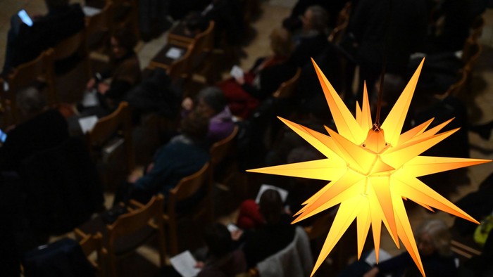 Großer gelber Stern als Dekoration, der über einem belebten Bereich hängt.