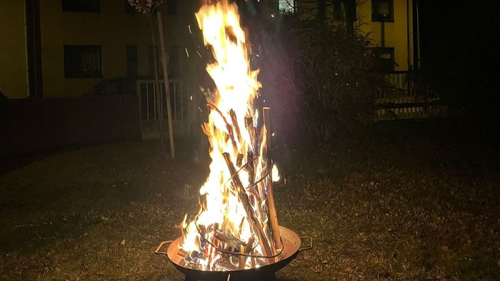Ein Feuer brennt in einem Metallbehälter im Freien.