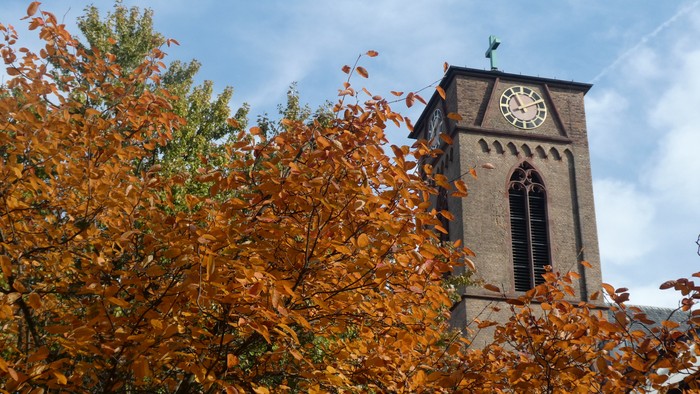 Herbstblätter vor Kirchturm mit Uhr