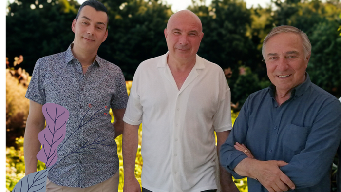 Trois hommes posent ensemble dans un jardin.