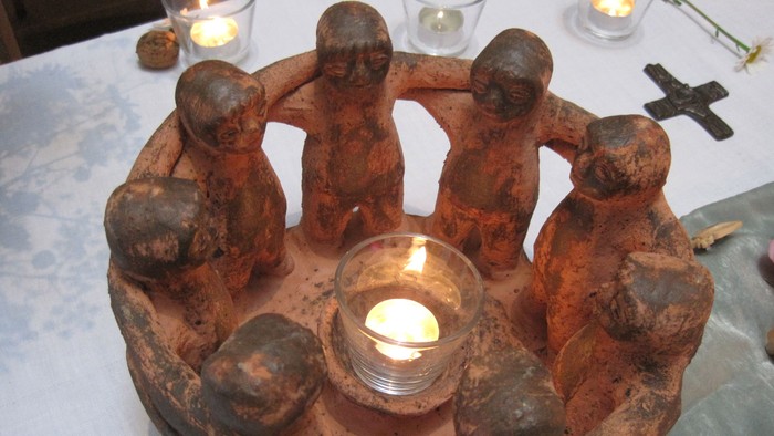 Eine Kerze in einem alten, keramischen Halter mit kleinen Figuren.