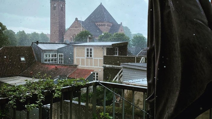 En kirke med tårn og en mørk paraply i forgrunden