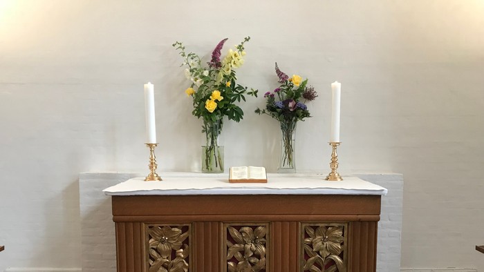 Altaret er dækket med blomster og lysestage.