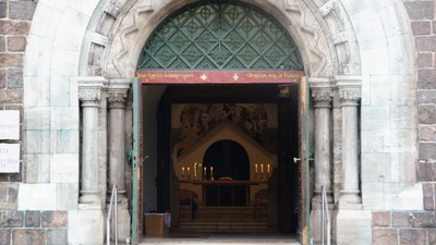 Der Eingang zu einer Kirche mit einem grünen Vordach und Kerzen im Inneren