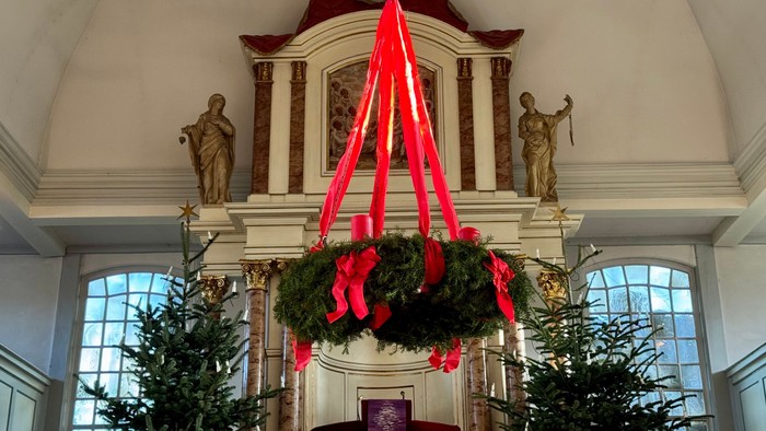 Kircheninneres mit Weihnachtskränzen und -bäumen geschmückt.