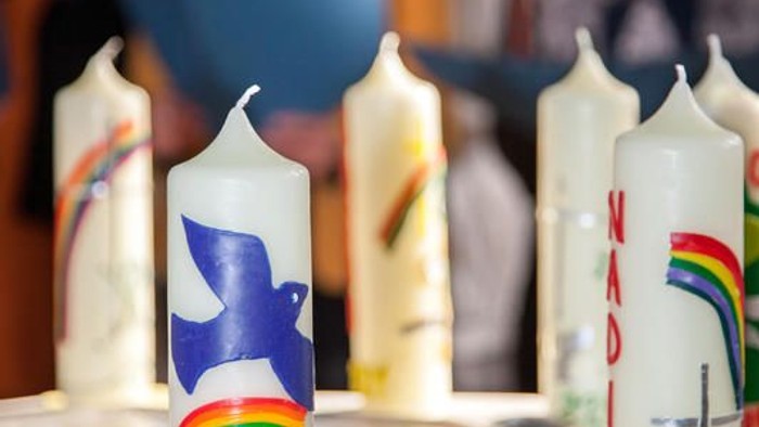 Kerzen mit Symbolen auf dem Tisch, Menschen im Hintergrund