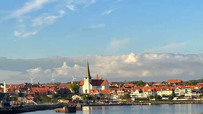 En rolig havneby med blå himmel og røde tagtegnende huse