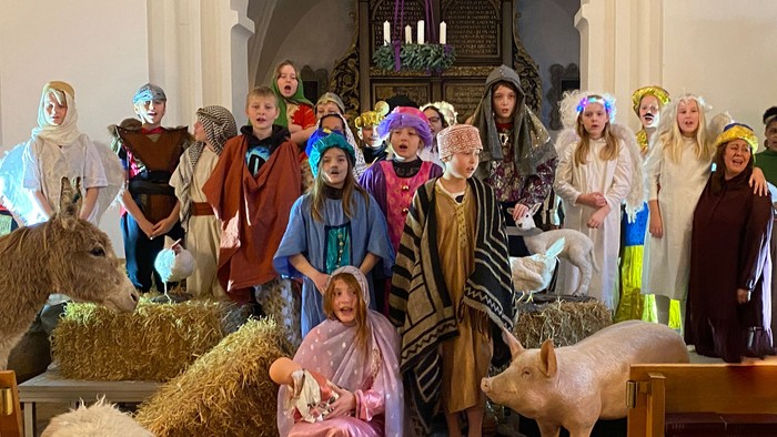 En gruppe børn i kostumer opfører et skuespil i en kirke.