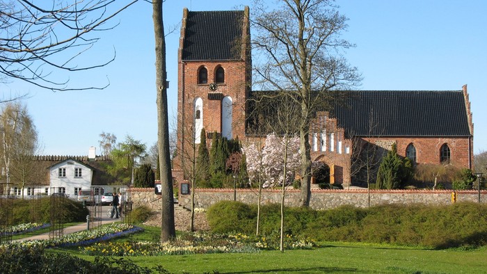 En kirke med tårn og murvej i en park
