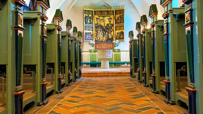 Indgang til kirke med høje buegange og lysende belysning