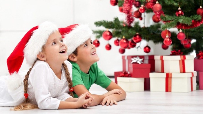 To børn i julestue med julerødder og julenisser.