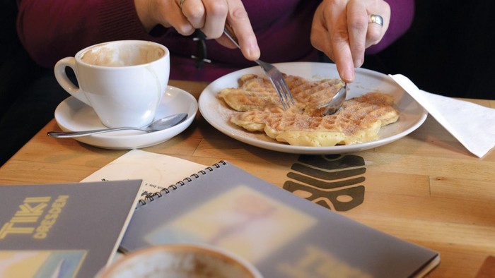 Person frühstückt Pfannkuchen und trinkt Kaffee am Tisch