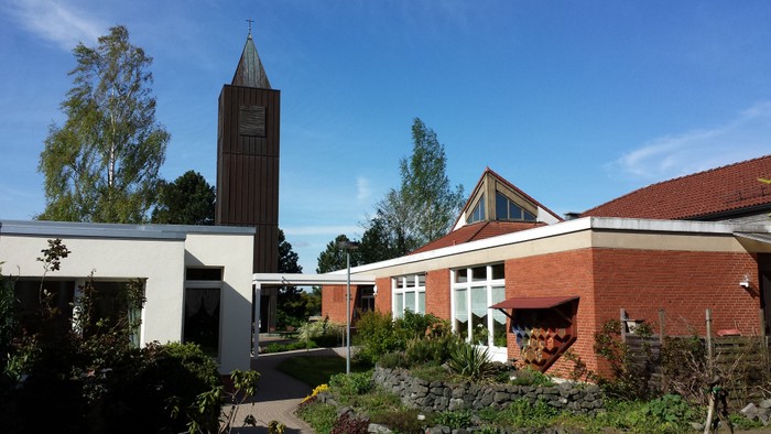 Moderner Bau mit hohem Uhrturm und gestaltetem Garten