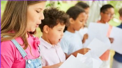 Eine Frau und vier Kinder singen gemeinsam aus einem Notenheft.