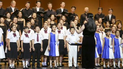 Kinderchor Beijing mit weißen Blusen und Hemden, dahinter jugendliche Sänger, beim Konzert