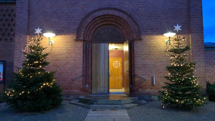 To adgang til kirken er der to juletræer med lys på hver side.