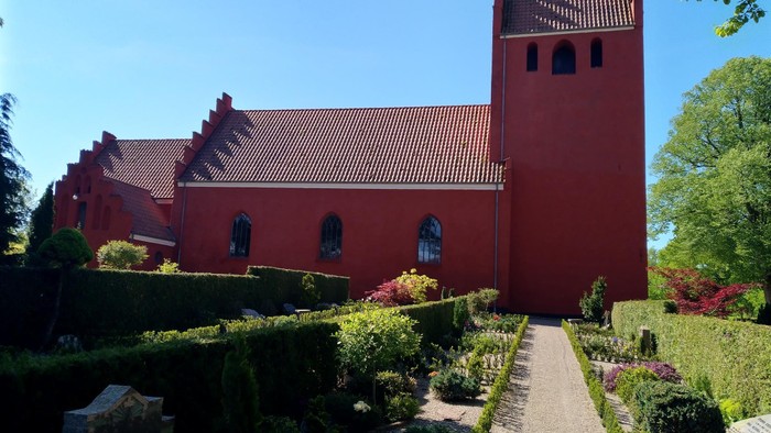Rødt kirke med tårn og hage.