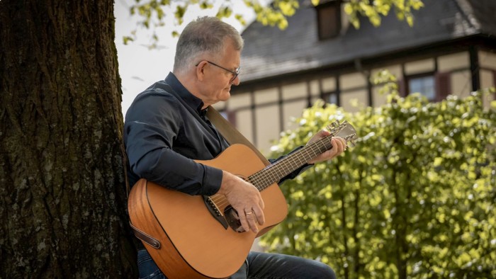 Mann spielt Gitarre unter einem Baum