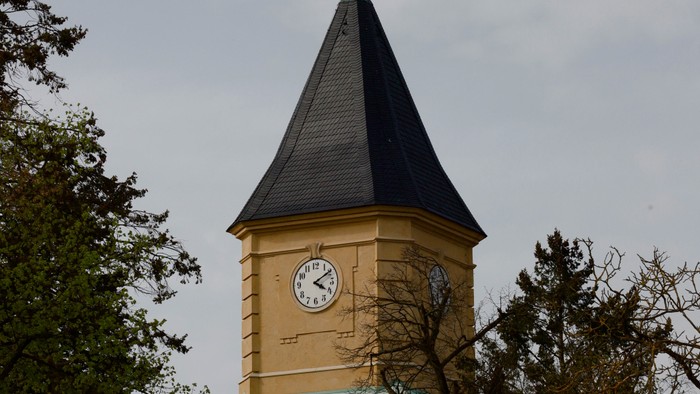 Der Uhrturm hat ein grünes Dach und eine Wetterfahne.