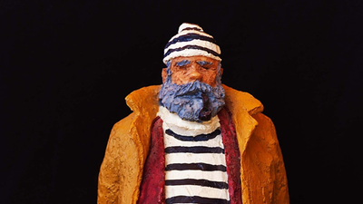 Håndlavet lerkrukkefigur af en skægget mand i vintage sømandsdragt med en stribede halstørklæde og hat.