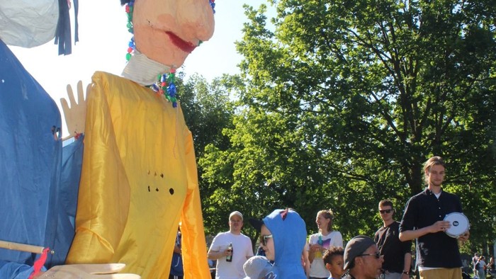 Menschen in Kostümen und Alltagskleidung versammeln sich im Freien.