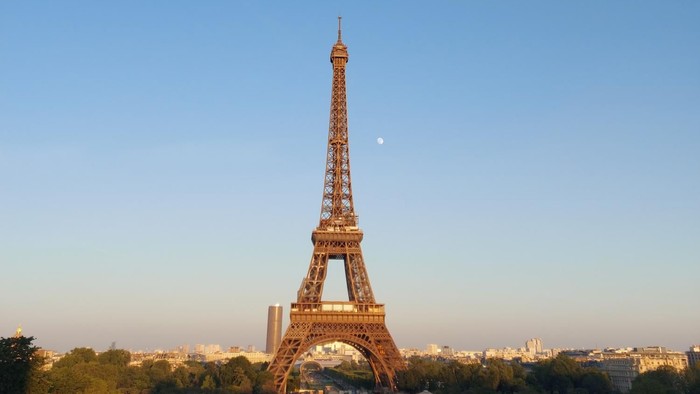 Eiffelturm bei Dämmerung beleuchtet mit Stadtpanorama im Hintergrund