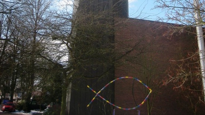 Hohe Kirche mit Turm und Kreuz vor blauem Himmel