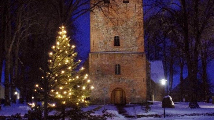 Weihnachtsbaum vor alter Kirche im Schnee
