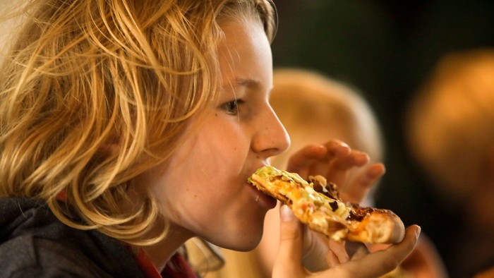 Et barn spiser en pizze.