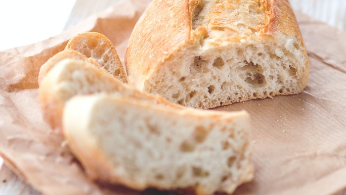 Ein Stück Brot liegt auf einem braunen Tuch auf einem Holztisch