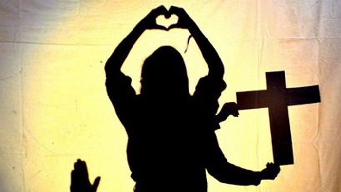 Schatten einer Person mit Kreuz und Herzzeichen