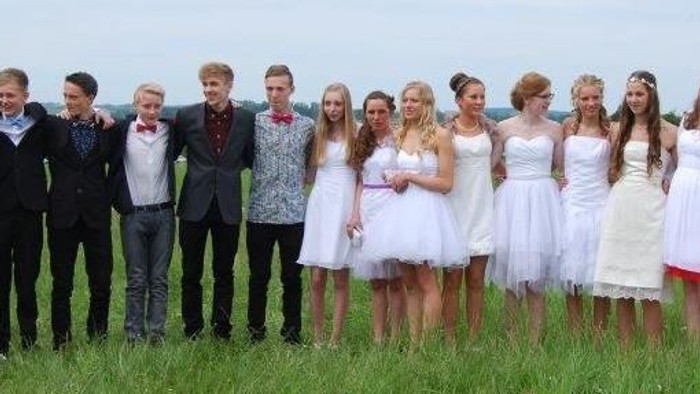 En gruppe unge mænd og kvinder poserer i en grøn mark.