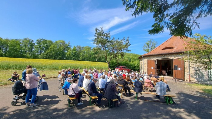 Gruppe von Menschen versammelt sich draußen in der Nähe einer Scheune.