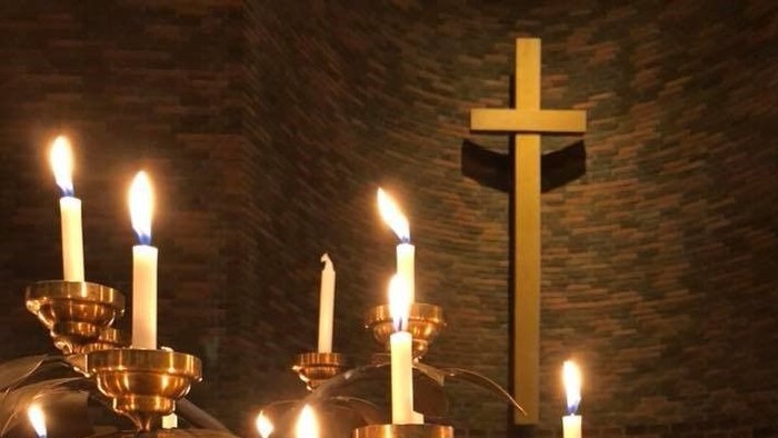 En kirke med mange lysstake og en korsformet lysestag.