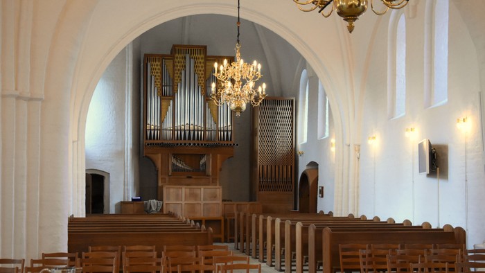 Indenrigspart af kirke med orgel og træbænke.