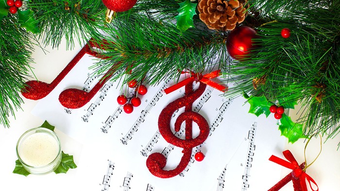 En festlig dekoration med grønne nåler, røde glitrende kugler og musiknoter til jul