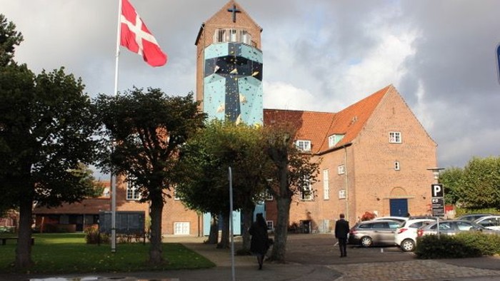 En kirke med tårn og dansk flag på en overcast dag