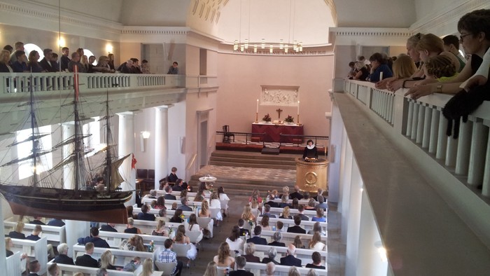 En stor sal med skibsmodel og folkemængde.