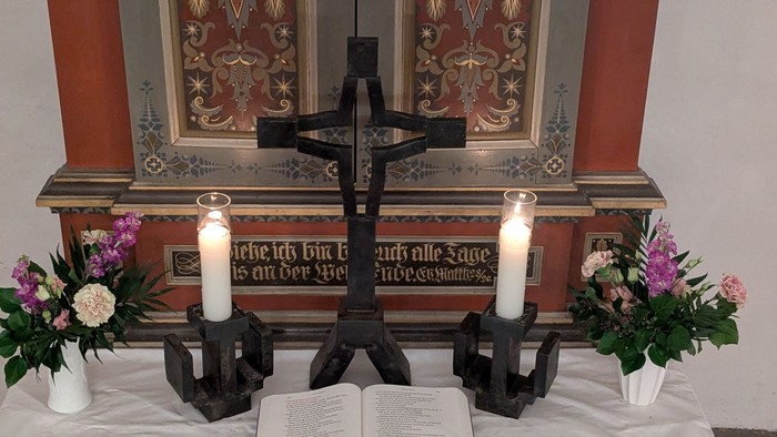 Altar mit Kreuz zwei Kerzen Blumen