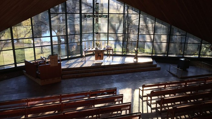 Moderne Kirche mit großen Glasfenstern und Holzgestühl