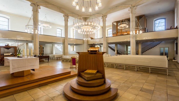 Großer, hell erleuchteter Raum mit hölzerner Podiumsstruktur und Kronleuchtern
