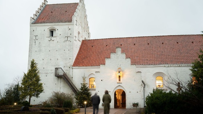 To personer går mod en oplyst kirkeindgang.