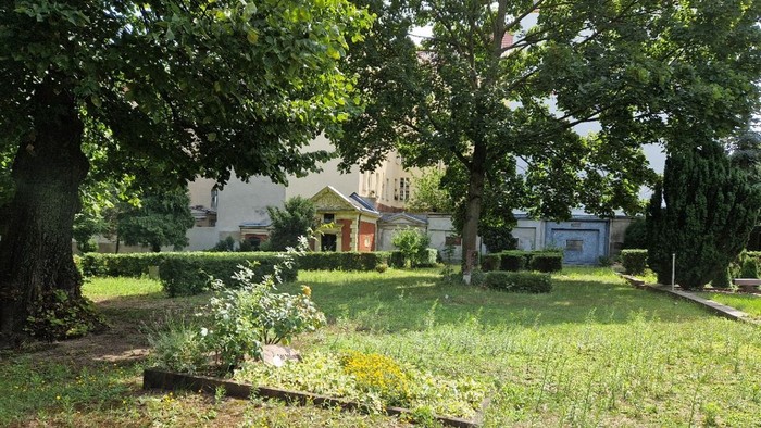 Blick auf das Mausoleum auf dem Magdalenenkirchhof im Hintergrund. Im Vordergrund Wiese, Bäume, und Hecken.