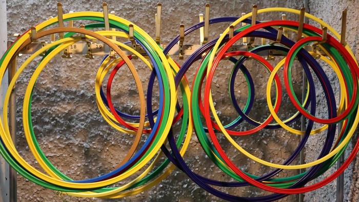 Bunte gestapelte Ringe, die in sich überlappenden Kreisformen auf Holzpfosten angeordnet sind.