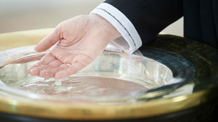 En hånd riner vand i en søppe.