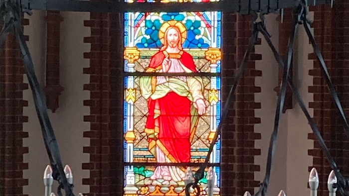 Buntes Kirchenfenster mit Darstellung von Jesus Christus in Rot und Gold